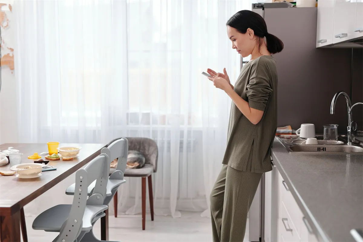 Woman in her kitchen checking the cost of small loans for bad credit on her phone