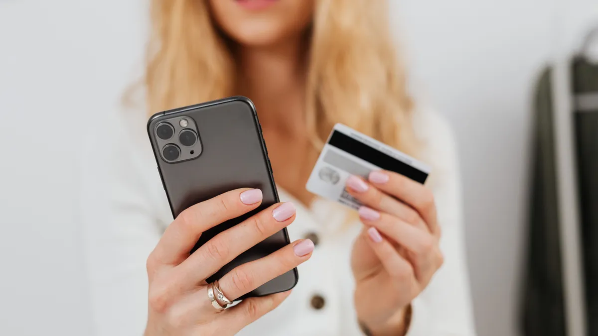 Woman holding her phone and bank card to borrow 300 dollars with an income-based check