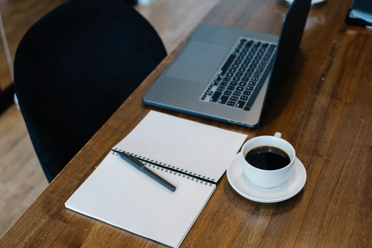 Laptop, blank notebook and coffee on a wooden table, working out the smallest amount that solves the problem before you get a small loan with bad credit